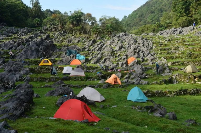 Colorful tents in rocky meadow with mountains