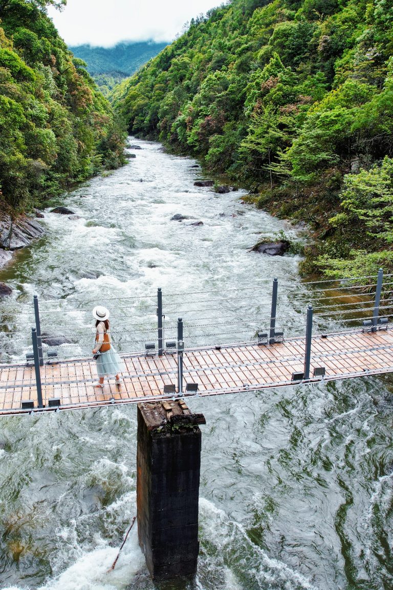 Woman on suspension bridge over rushing stream