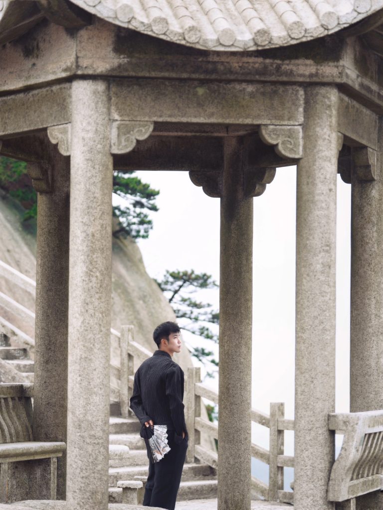 Figure in black standing near stone pavilion