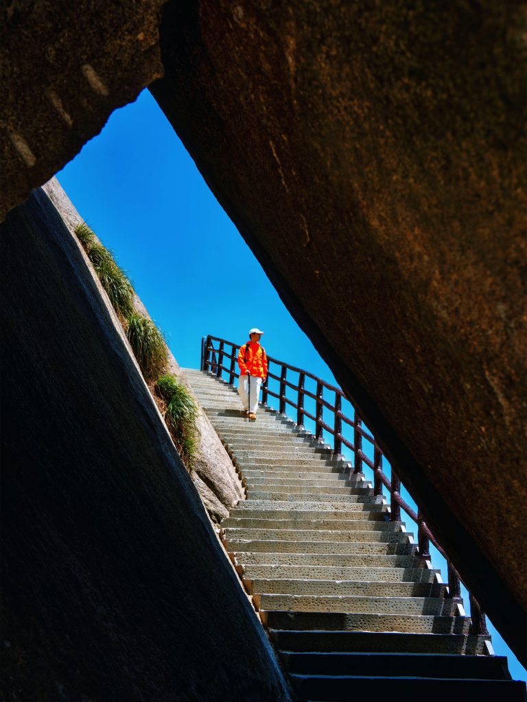 Hiker ascending steep trail along cliff