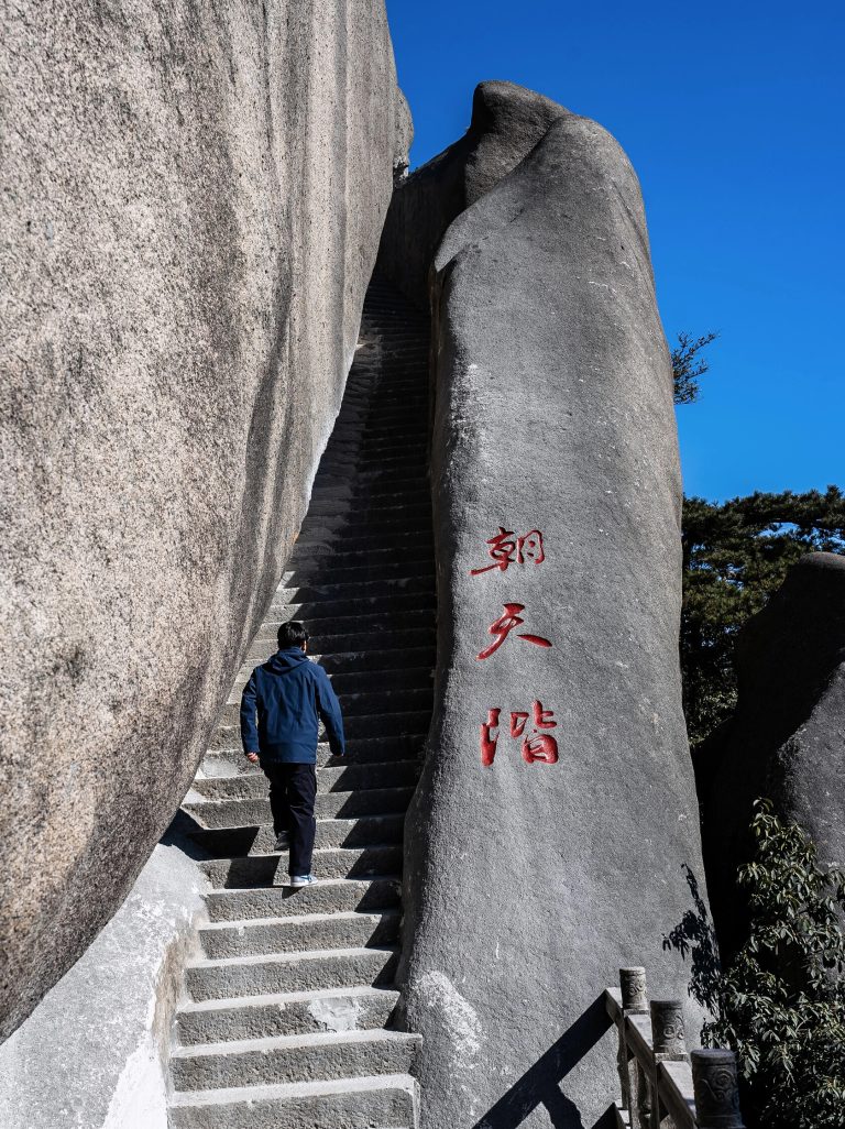 Person climbing stone steps with carved characters