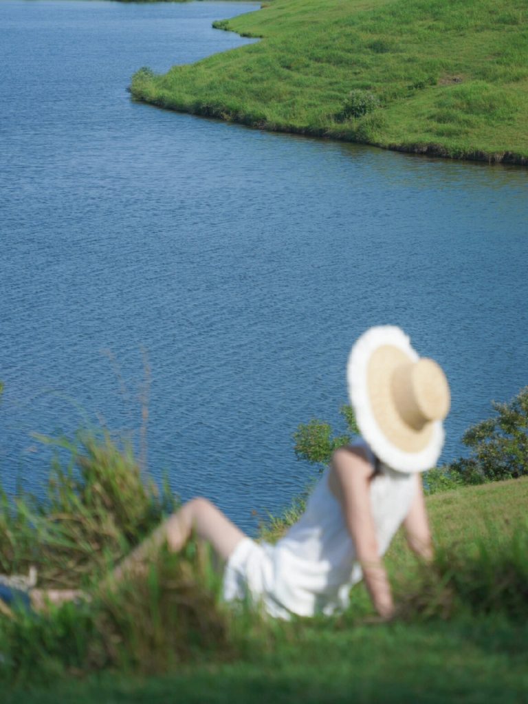 Person sitting by lakeside in hat