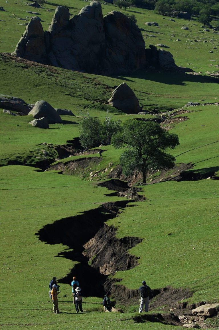 Group hiking on green grassland with rocky backdrop