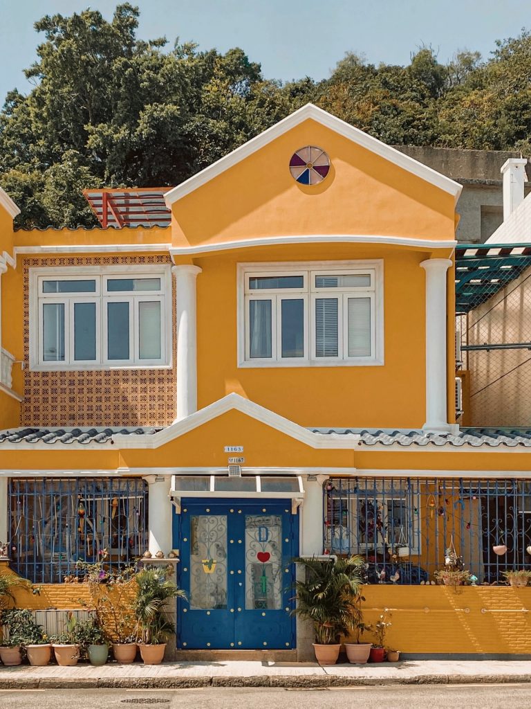 Bright yellow house with blue door and plants