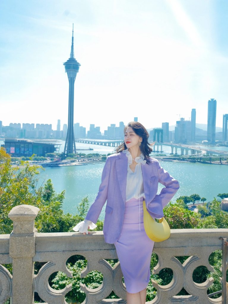 Woman in purple suit by waterfront tower