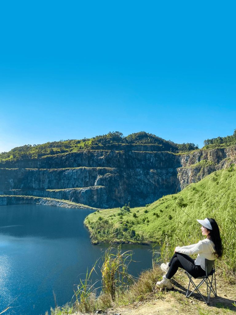 Person sitting in a chair overlooking a stunning turquoise lake surrounded by cliffs