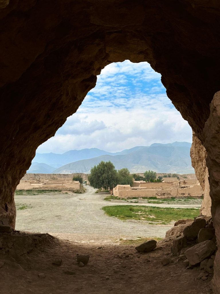 A cave entrance overlooking a sparse landscape, hinting at ancient dwellings and the harsh beauty of this Desert landscape adventure.