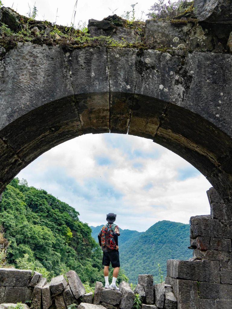 A lone traveler stands before an ancient stone bridge, reflecting on the historical paths of the Ancient Silk Road.